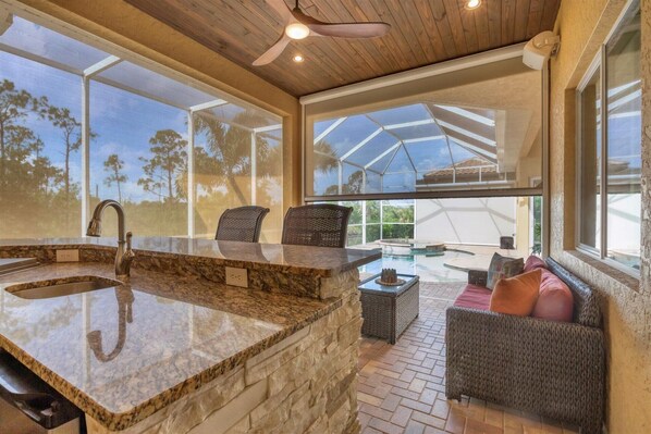 A kitchen with a granite countertop, a built-in sink, and a ceiling fan.