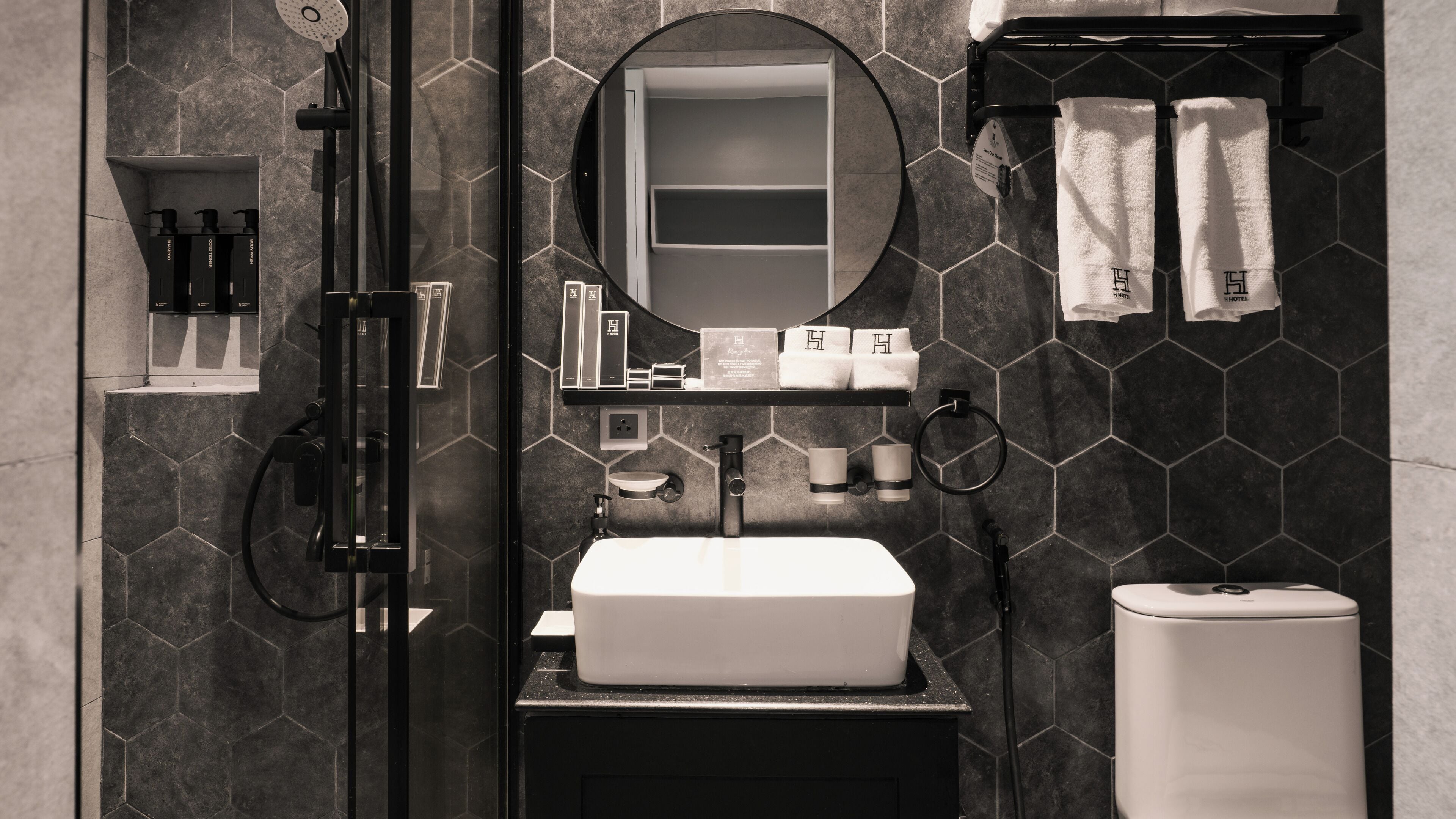 A modern bathroom with a glass-enclosed shower, a white sink, and a mirror above it.