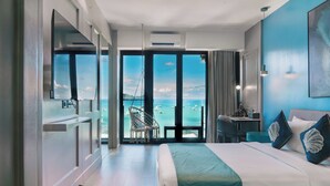 Habitación de hotel con una cama grande, un escritorio, una silla y vista al océano.