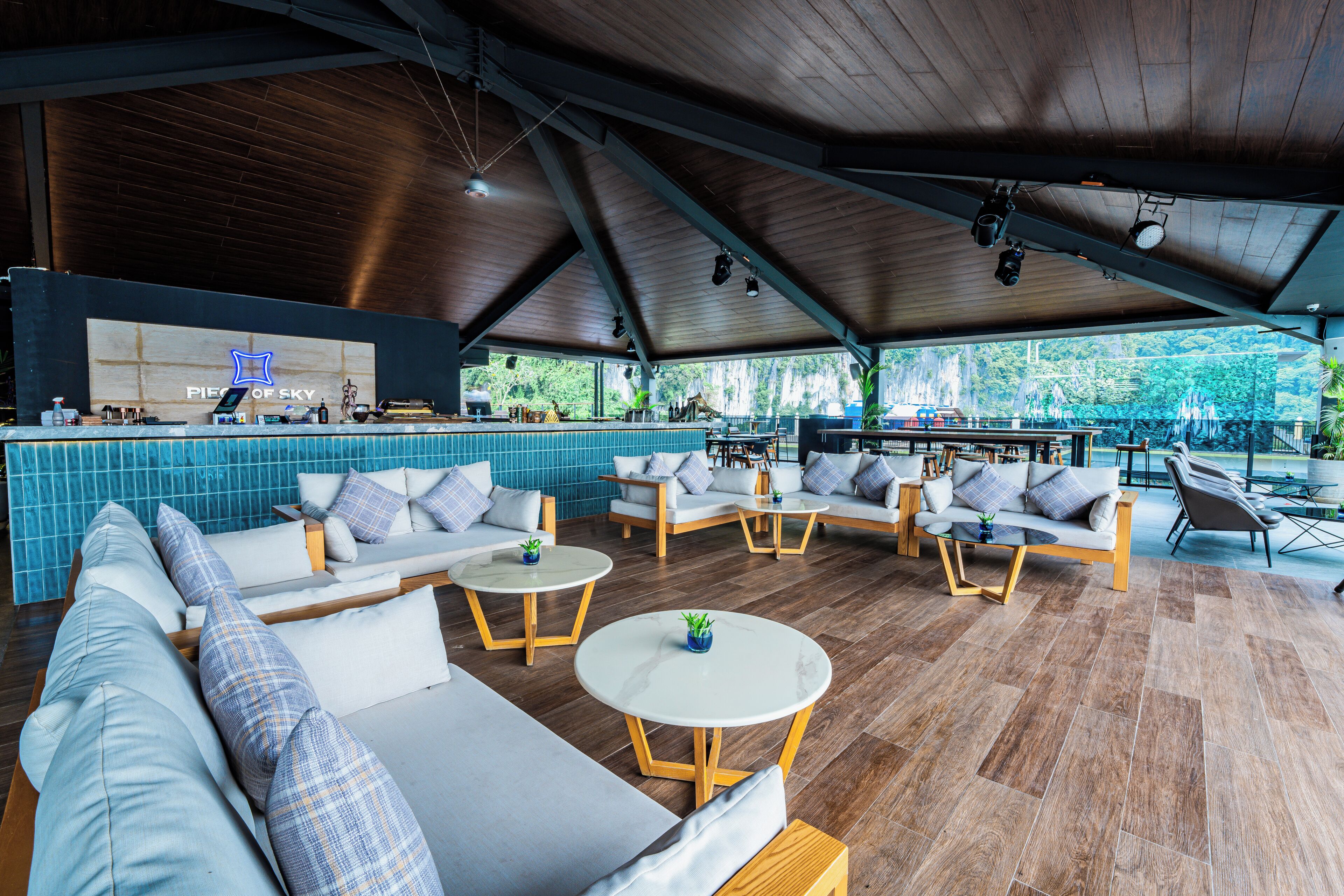 A spacious outdoor lounge area with multiple seating options, a bar, and a view of the outdoors.
