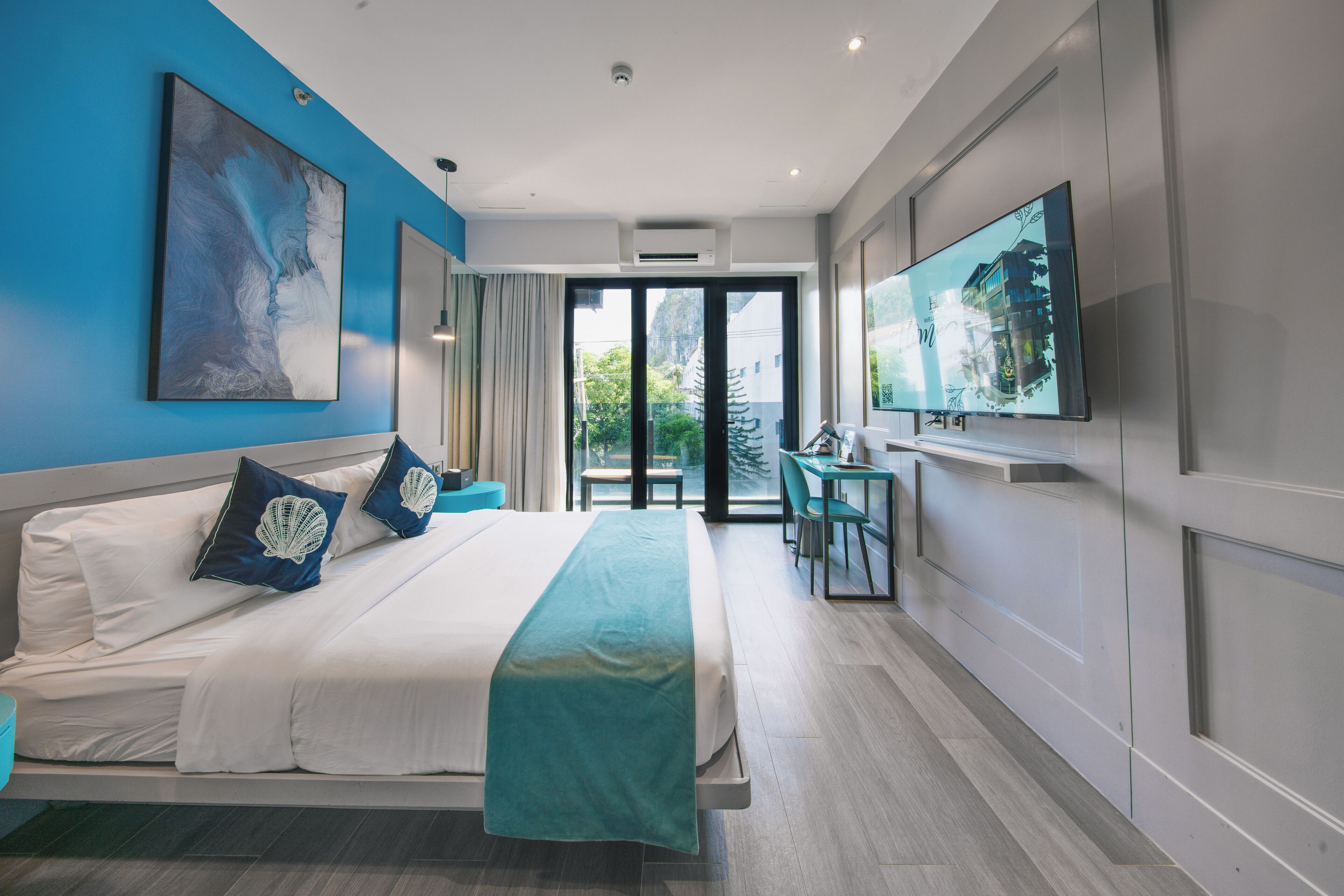 A modern hotel room with a large bed, a desk, a television, and a view of the outdoors.