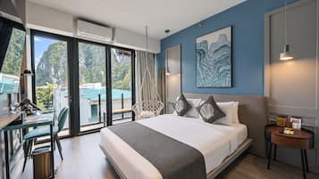 A modern hotel room with a large bed, a desk with a chair, a view of the outdoors, and a painting on the wall.