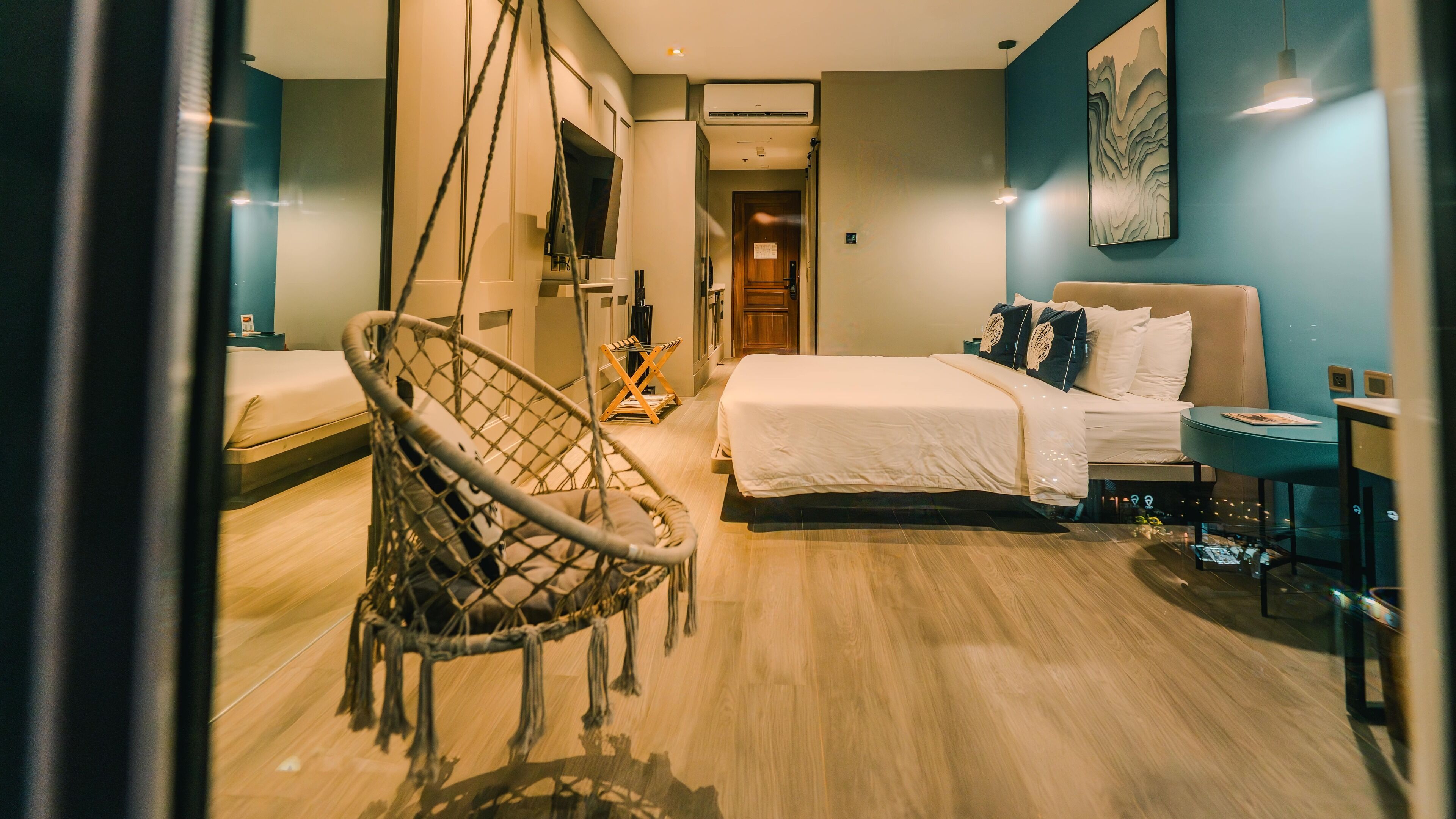 Una camera d'albergo moderna con un letto, una poltrona sospesa, una scrivania e una TV.