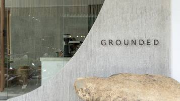 Un mur de pierres sur lequel est écrit le mot « GROUNDED » et un gros rocher devant.