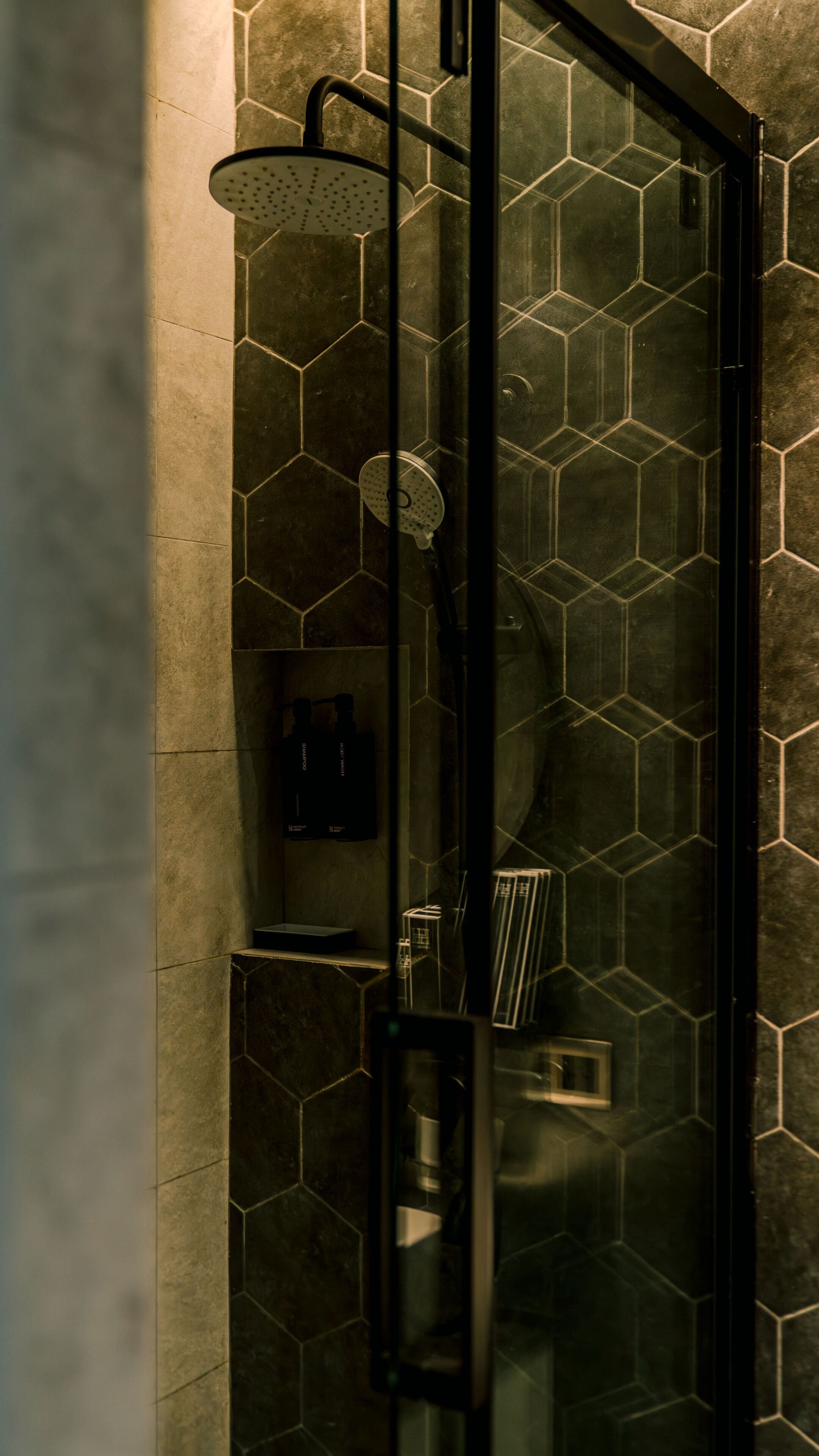 A glass-enclosed shower with a hexagonal tile pattern on the walls.