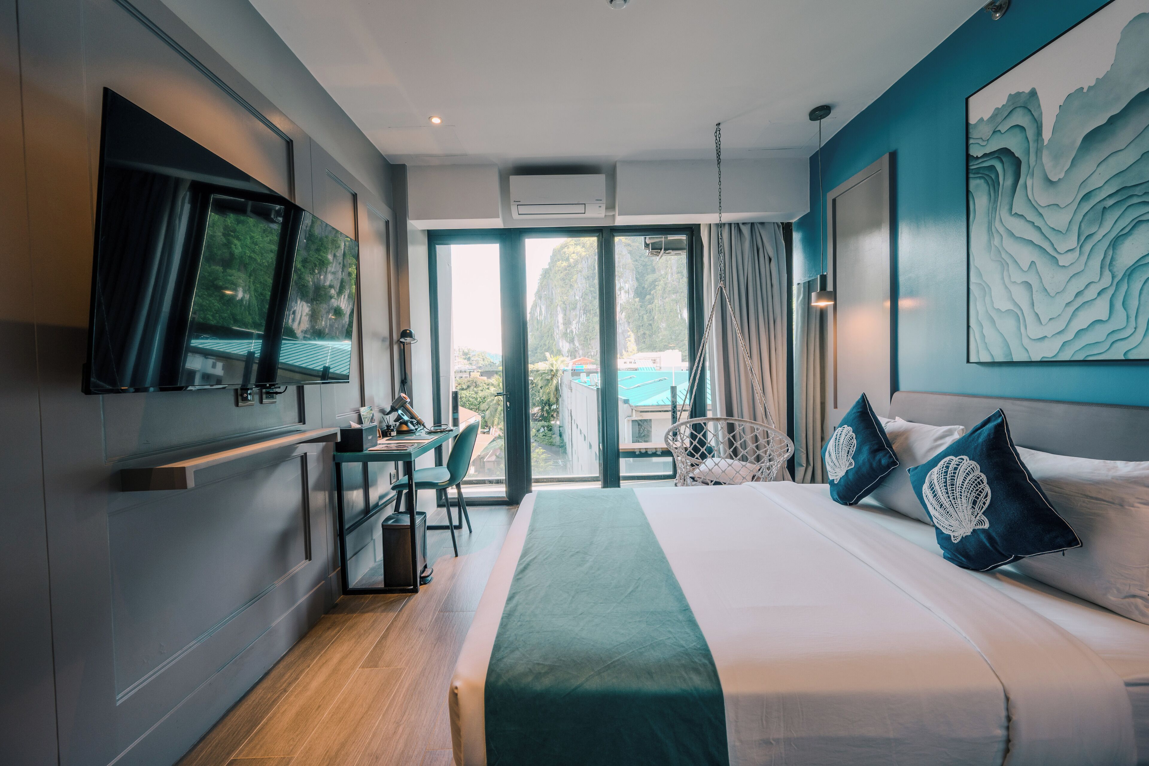 A modern hotel room with a bed, a desk, a chair, and a large window.