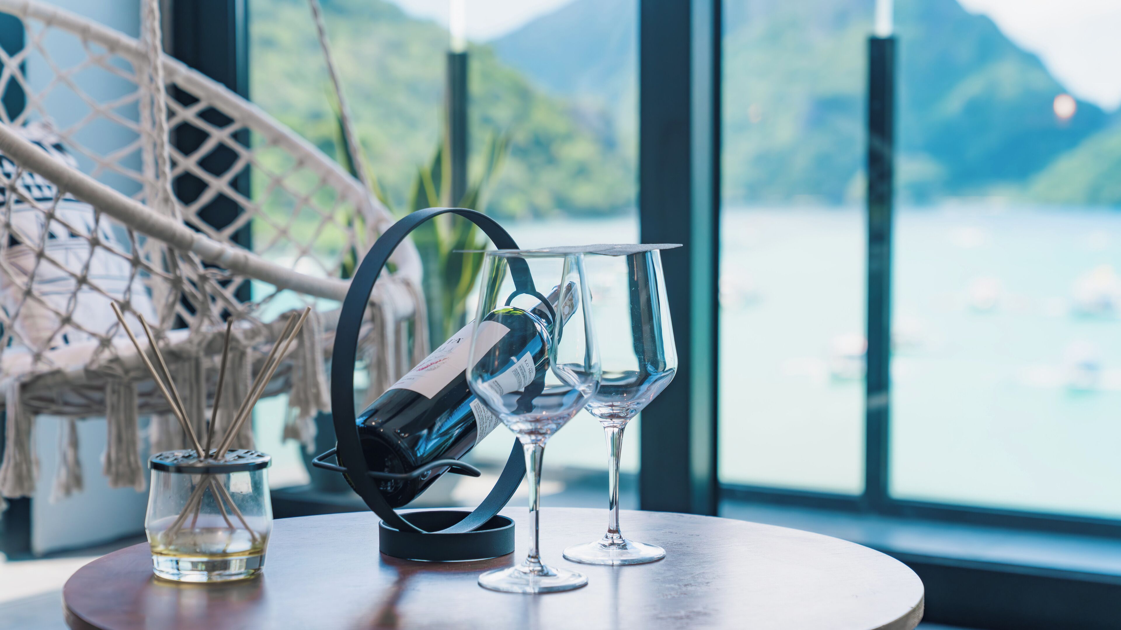 A table with a bottle of wine, two wine glasses, and a glass of water.