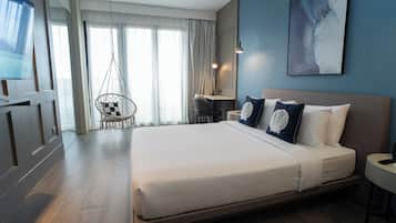 A modern hotel room with a large bed, a desk, and a hanging chair.
