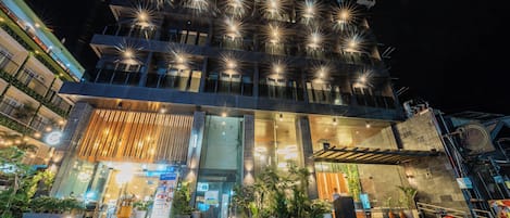Ein mehrstöckiges Hotel mit modernem Design, das eine auffällige Eingangsfront mit Stufen und einer überdachten Fläche aufweist.