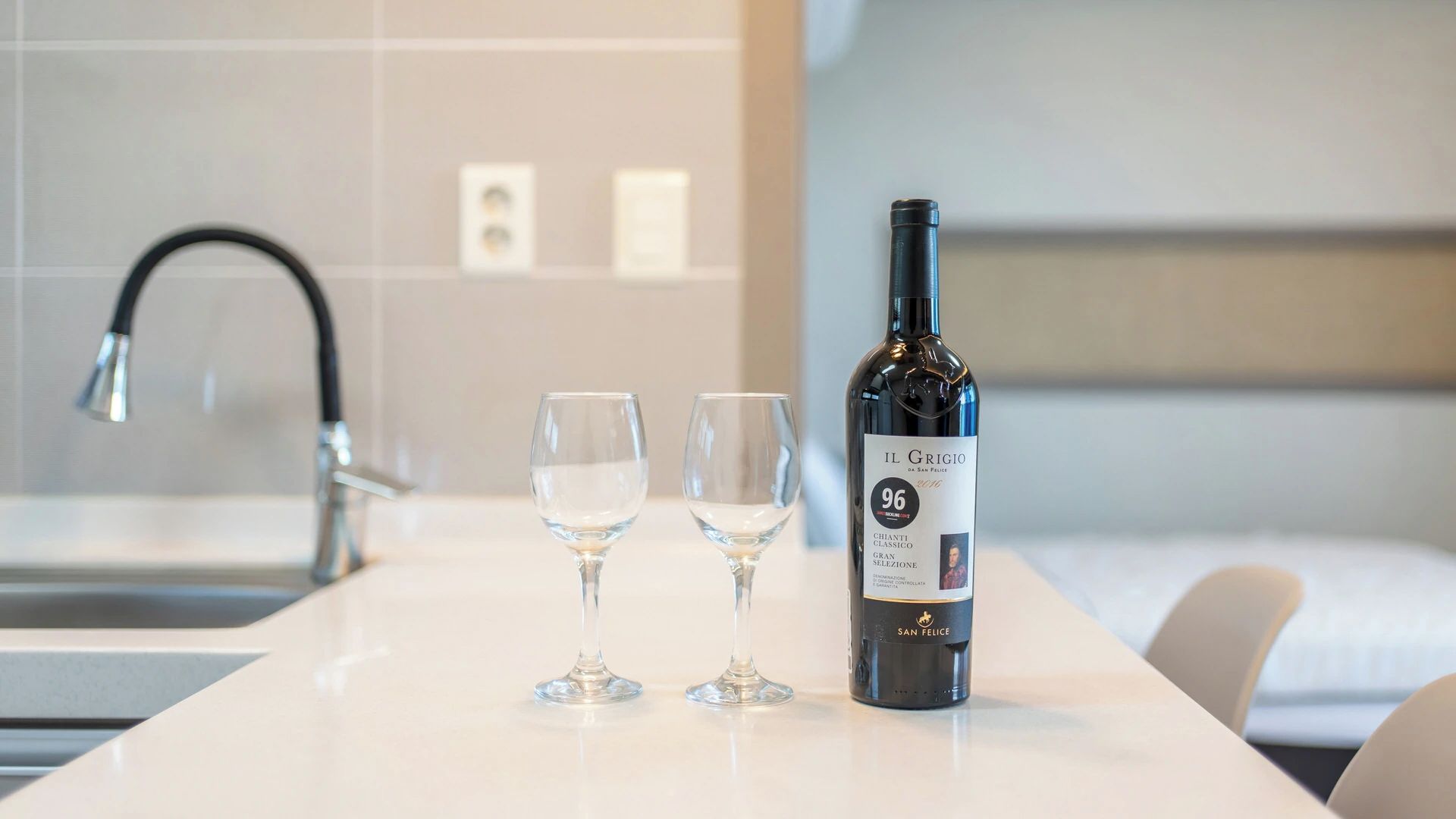 A bottle of wine and two glasses on a white countertop in a hotel room.