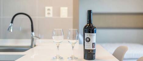 A bottle of wine and two glasses on a white countertop in a hotel room.