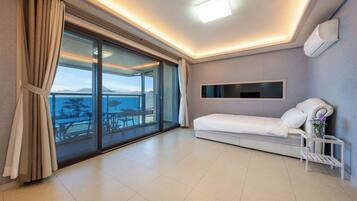 Een moderne hotelkamer met een balkon, een bed, een televisie en een klein tafeltje met een vaas.
