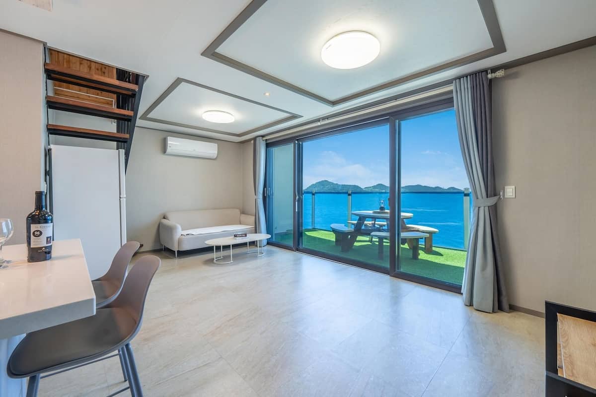 Ett modernt hotellrum med en matplats, en soffa och en balkong med utsikt över havet.