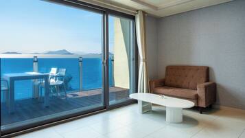 Una habitación moderna con un amplio ventanal corredero que da a un balcón con vistas al mar y a las montañas.