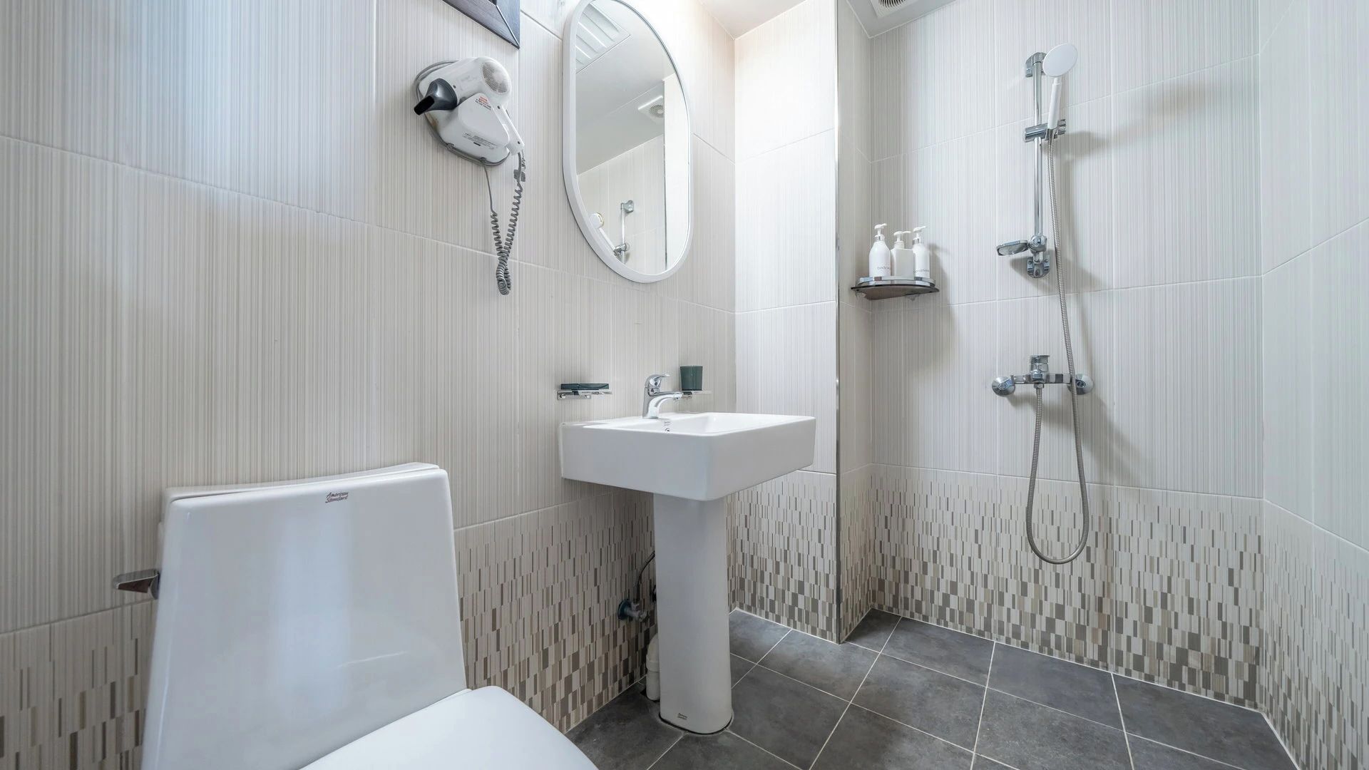 Ein modernes Badezimmer mit Toilette, Waschbecken, Spiegel und Dusche.