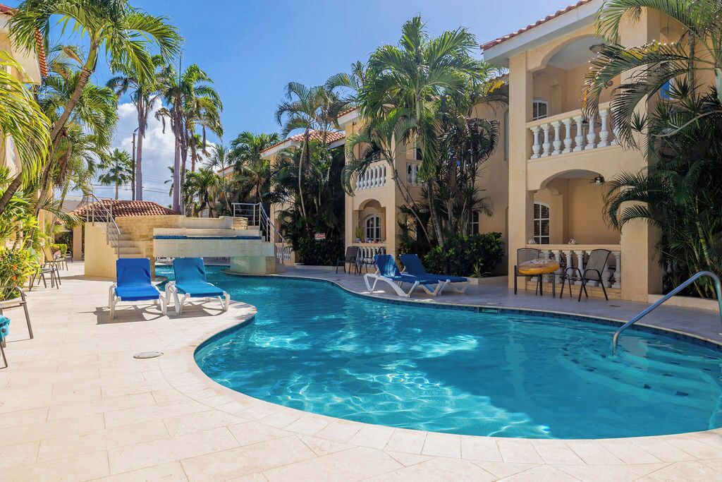 A pool area with lounge chairs and palm trees.