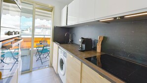 Eine moderne Küche mit Waschmaschine, Kaffeemaschine und Essbereich mit Tisch und Stühlen.