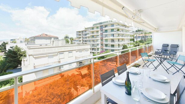 Ein Balkon mit Esstisch, der auf einen Wohnbereich mit mehrstöckigen Gebäuden blickt.