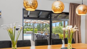 A dining area with a wooden table, two vases with white flowers, and hanging spherical light fixtures. - Villa Venezia by Interhome (Labin)