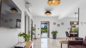 A modern hotel lobby with a wooden reception desk, a seating area with a couch and chairs, a dining table, and a large window offering a view of the outdoors. - Villa Venezia by Interhome (Labin)