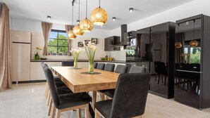 A modern kitchen with a wooden dining table, black chairs, and pendant lights. - Villa Venezia by Interhome (Labin)