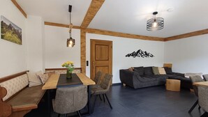 Una sala de estar moderna con comedor, que presenta techo de madera, un conjunto de sofá y una mesa de comedor con sillas.