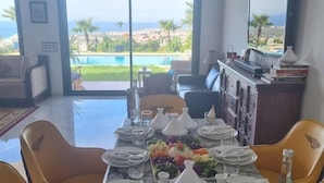 Un coin repas avec une table dressée pour quatre personnes, donnant sur une piscine et offrant une vue panoramique.