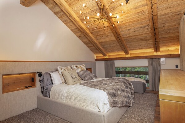 A bedroom with a sloped ceiling, a bed with a fur throw, and a built-in shelf.