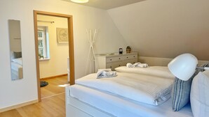 A bedroom with two beds, a dresser, a mirror, and a ceiling light. - Ferienwohnung Alvine - Dubnitz - Doppelhaushälfte Alwine (Sassnitz)