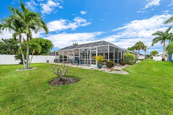 A greenhouse-style structure with a glass roof, surrounded by a well-maintained lawn and palm trees.