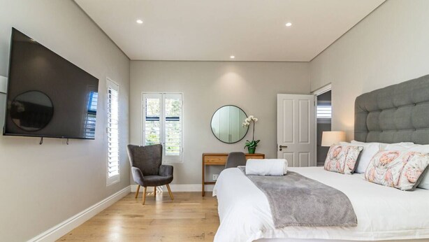 A bedroom with a bed, a desk, a chair, a TV, and a door.