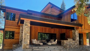 Una casa moderna de dos pisos con un patio cubierto, mobiliario exterior y escalones de piedra.