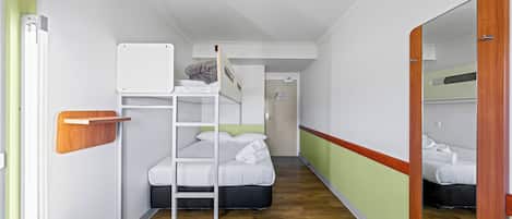 A compact hotel room with a bunk bed, a wooden shelf, a mirror, and a small wooden table.