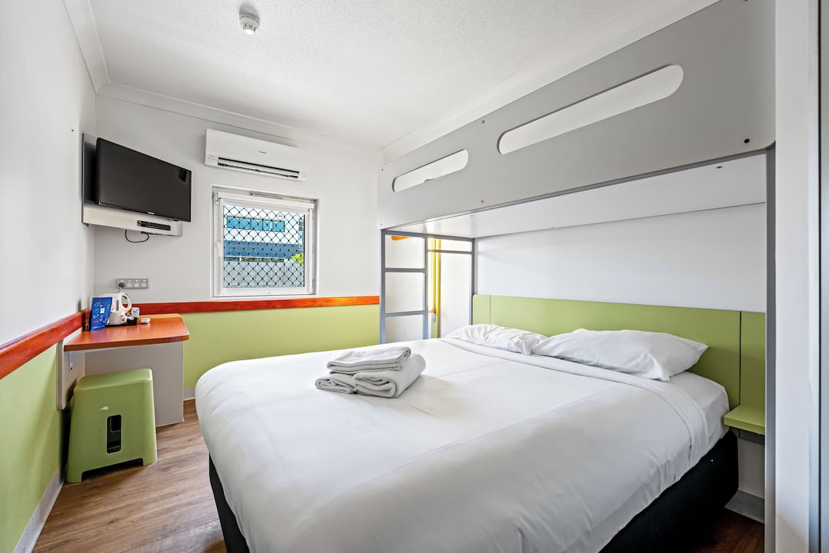 Hotellihuone, jossa on sänky, työpöytä, televisio ja ikkuna, josta on näkymä.