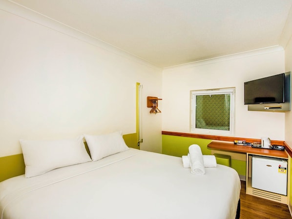 A hotel room with a bed, a desk, a television, and a small refrigerator. - Imperial Motel Windsor (Windsor)