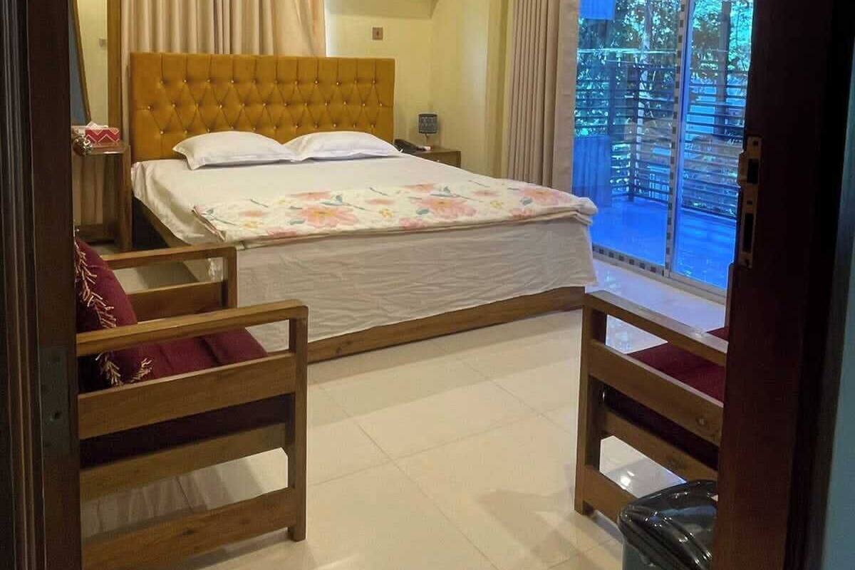 A bedroom with a bed, a ceiling fan, an air conditioning unit, a window with curtains, and a view of the outdoors.