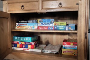 A wooden cabinet with multiple shelves containing various board games.
