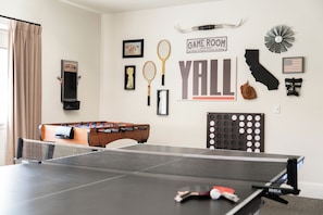 Quarto com mesa de pingue-pongue, mesa de futebol de mesa e diversos artigos de coleção esportiva na parede.