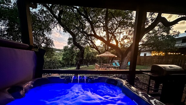 A hot tub with a view of a backyard at sunset. - 4BR Sleeps 12 - Hottub Firepit - 1 Mile to Lake & River! (Canyon Lake)