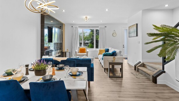 Un espace de salle à manger moderne avec une table centrale, des chaises bleues et un lustre.