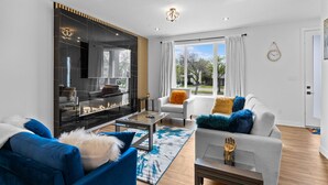 Un salon moderne avec une cheminée, un canapé, une table basse et une vue sur l’extérieur.