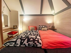 Een slaapkamer met een bed, nachtkastje, spiegel en een plank met foto's.