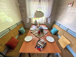 Een gezellig eetgedeelte met een houten tafel gedekt voor twee personen, omringd door zachte banken met kussens.