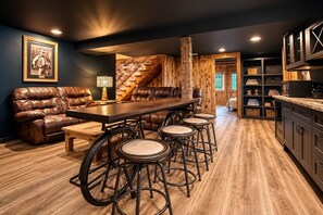 Eine moderne Küche mit Holzboden, einer Bar mit Hockern, einem Ledersofa und einer Treppe.