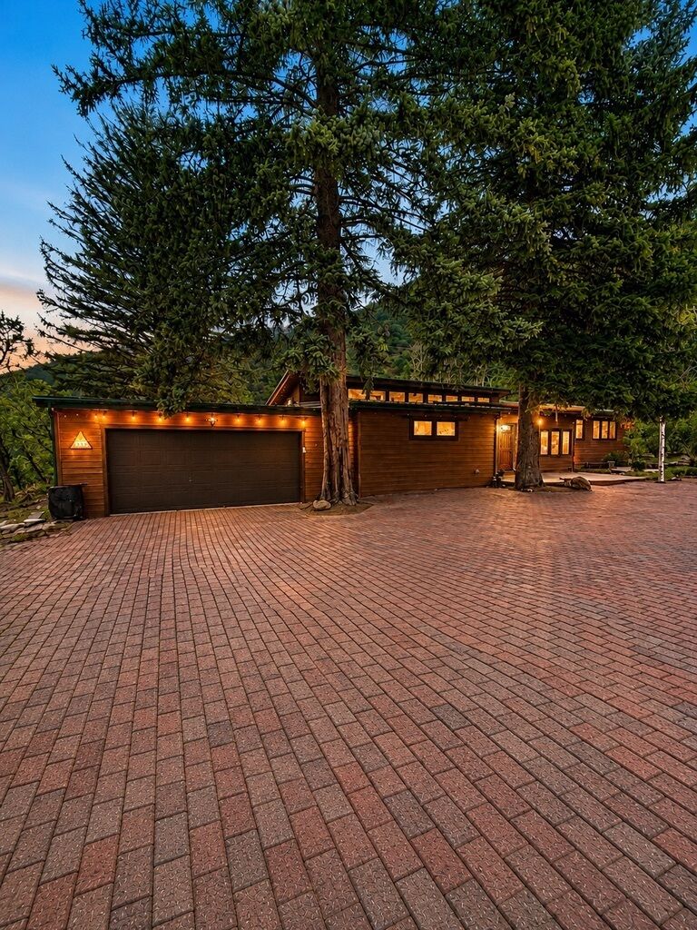 A two-story building with a garage, paved driveway, and a large tree in front.