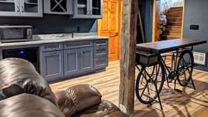 Eine moderne Küche mit grauen Schränken, einer Mikrowelle und einem Spülbecken. Eine Holztür und ein Fahrrad befinden sich im Raum.