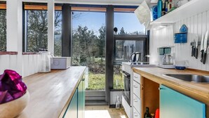 Une cuisine moderne dotée de grandes fenêtres, de poutres en bois et offrant une vue sur l’extérieur.