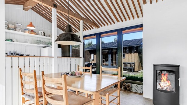 Une cuisine moderne avec des meubles en bois, une table à manger et une grande fenêtre.