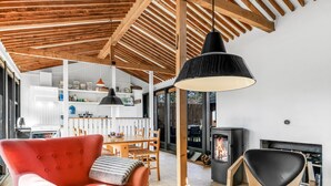 Un salon chaleureux avec un canapé rouge, une table à manger en bois et une suspension noire.