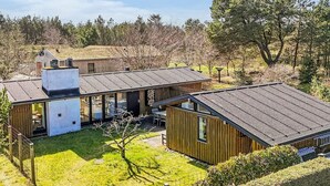 Une maison moderne dotée d’une grande cour ouverte, d’un garage séparé et d’un petit bâtiment indépendant.